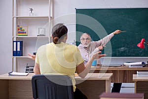 Old teacher and young male student in the classroom