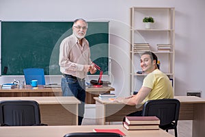 Old teacher and young male student in the classroom
