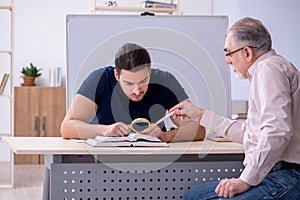 Old teacher and young male student in the classroom