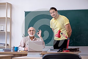 Old teacher and young male student in the classroom