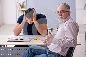 Old teacher and young male student in the classroom