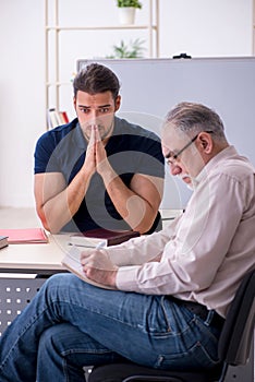 Old teacher and young male student in the classroom