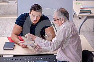 Old teacher and young male student in the classroom