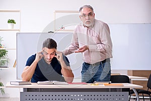 Old teacher and young male student in the classroom