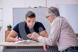 Old teacher and young male student in the classroom