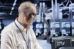 Old technician coding in data center
