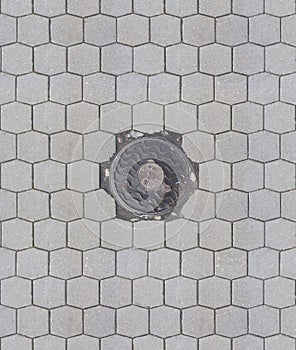 Old teel sewer manhole on the cobblestone road pavement