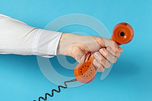 Old telephone receiver in hand over blue background