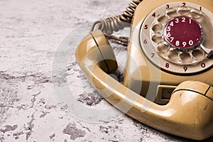 An old telephone with rotary dial on grunge background