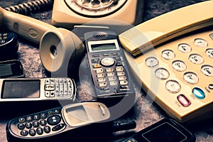 Old telephone with rotary dial, landline and obsoleted cellphone on a grunge background