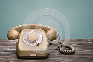 Old telephone stands on the wooden boards isolated on a blue background