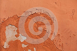 Old terracotta painted stucco wall with chipped paint. Background texture