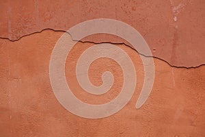 Old terracotta painted stucco wall with cracked plaster. Background texture photo