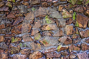Old texture of stacked stone wall have bright green moss along the rock
