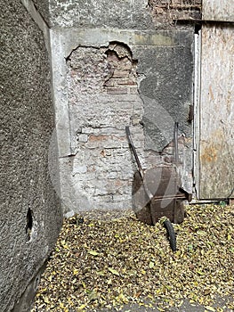 Old textured stone brick yard wall, fallen autumn leaves old rusty wheel car farm cart.