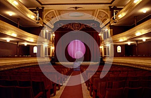 old theater interior from the year 1930 with red seats and curtain with light in a circle and lights focusing buenos aires