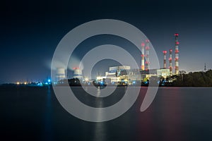 Old thermal 450 megawatt power plant at night with artificial lake on foreground photo