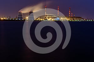 Old thermal 450 megawatt power plant at night with artificial lake on foreground photo