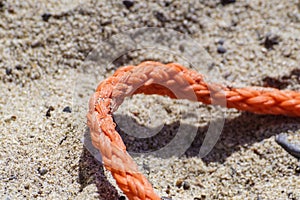 Old thick nautical rope on the sand ground .