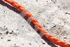 Old thick nautical rope on the sand ground .