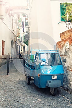 Old three-wheeled car parked on narrow street