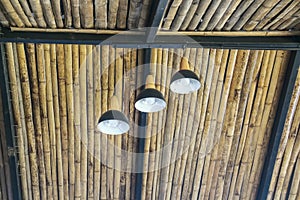 Old three white electric light lamps hanging on ceiling bamboo roof interior on background
