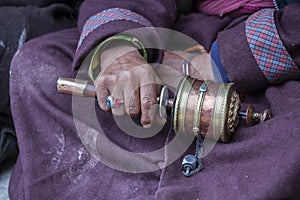 Old tibetan woman holding buddhist prayer wheel, Ladakh, India, close up