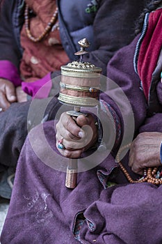 Old tibetan woman holding buddhist prayer wheel, Ladakh, India, close up