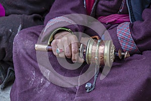 Old tibetan woman holding buddhist prayer wheel, Ladakh, India, close up