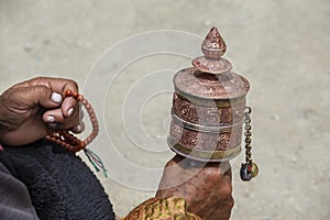 Old tibetan woman holding buddhist prayer wheel, Ladakh, India, close up