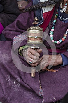 Old tibetan woman holding buddhist prayer wheel, Ladakh, India, close up