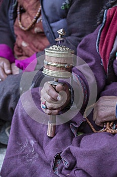 Old tibetan woman holding buddhist prayer wheel, Ladakh, India, close up