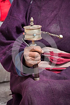 Old Tibetan woman holding buddhist prayer wheel in Lamayuru Gompa, , Ladakh, India.
