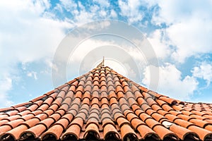 Old tiled roof with sky in background.