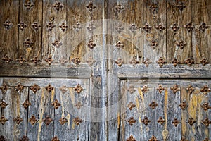 Old and time-worn solid wooden door with decorative metal elements