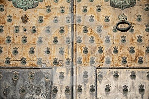 Old and time-worn solid wooden door with decorative metal elements