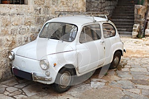 Old-timer white small italian car parked in an all