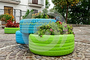 Old tires that are painted in assorted colors and used for a flower planter, modern garden photo