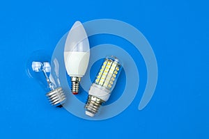 From old to new, fluorescent and LED light bulbs together, blue background. Energy saving concept. Flat lay, top view