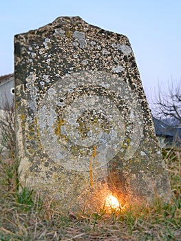 Old tombstone with lit candle