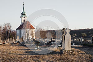 Old Tombstones in public cemetery in European village with chapel on background on sunset. Blank tombstone and graves in ancient