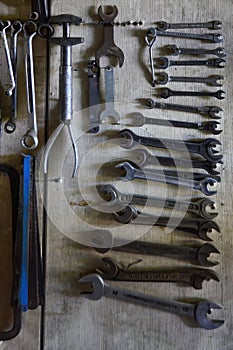 Old tools hanging on the wall on the handmade panel