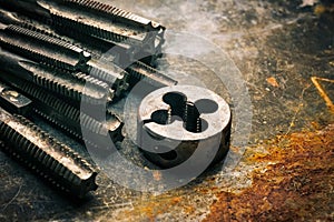 Old tools ,Taps and Dies, Cutting Tools for hand or machine tapping of through or blind holes on rusty metal plate background at