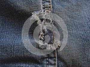 Old torn denim texture background. Fringe on worn blue jeans. Close-up.