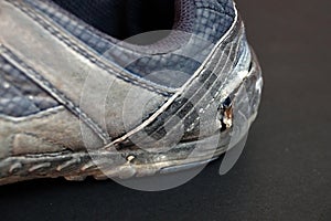 Old torn men`s sneaker on a black background