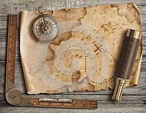 Old torn treasure map with compass and spyglass top view still life. Adventure and travel concept.