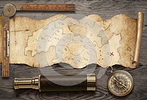 Old torn treasure map with compass and spyglass top view still life. Adventure and travel concept. Mixed media.