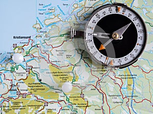 Old tourist compass lying on a map of Norway