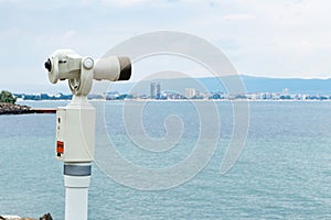 Old touristic telescope with blurred city and sea landscape background