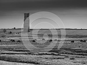 Old tower isolated behind the sea wall in the field